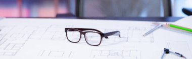 selective focus of eyeglasses on blueprint in architectural agency, banner clipart