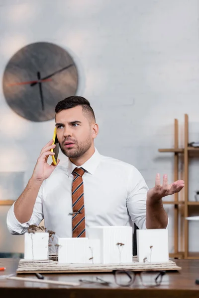 Serious Architect Gesturing While Talking Smartphone Architectural Project Blurred Foreground — Stock Photo, Image