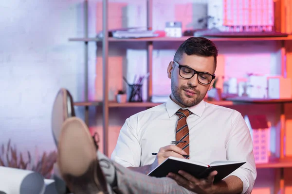 Arquitecto Sonriente Sentado Con Las Piernas Escritorio Escritura Cuaderno — Foto de Stock