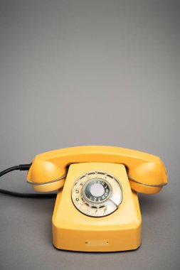 Gri arkaplanda sarı ve eski telefon 