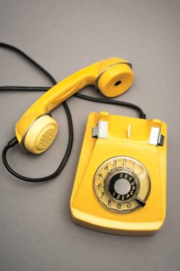 Gri arkaplanda retro ve sarı telefonun üst görünümü