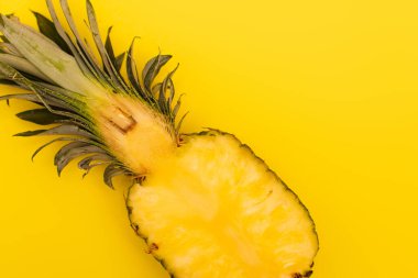 Sarı üzerine izole edilmiş taze ananas ve olgun yarısının üst görüntüsü.