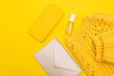 Tırnak cilasıyla şişenin en üst görüntüsü, şık telefon, giysi ve sarı üzerine izole edilmiş zarf gibi durumlar için. 
