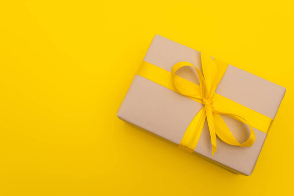 too view of wrapped present with ribbon on bow isolated on yellow