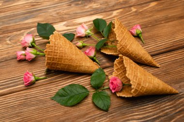 Tahta yüzeyde waffle külahında yaprakları olan pembe çiçekler.