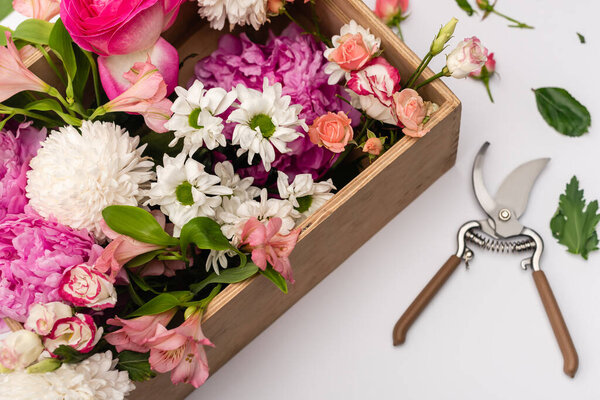 ручные обрезки возле деревянной коробки с цветущими цветами на белом