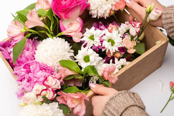 cropped view of woman holding box with variety of flowers on white