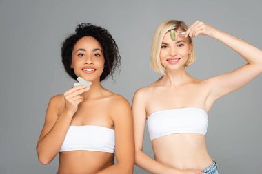 Neşeli çok kültürlü kadınlar gua sha ve yeşim taşı kullanıyorlar. 