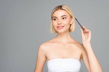 Gri renkte rimel için aplikatör tutan gülümseyen kadın. 