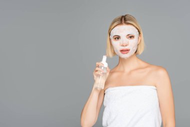 Young woman with sheet mask holding cleansing foam isolated on grey  clipart