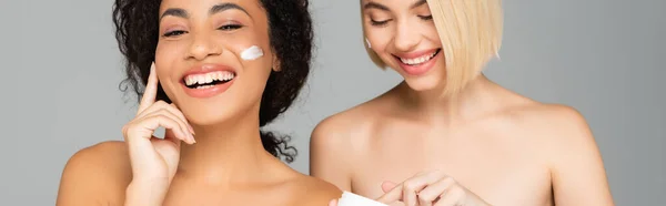 Cheerful Multicultural Women Applying Cosmetic Cream Isolated Grey Banner — Stock Photo, Image
