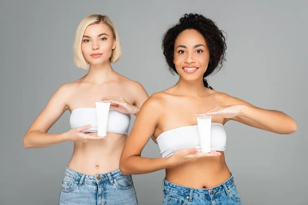 Mujeres Multiétnicas Sosteniendo Tubos Con Crema Cosmética Aislada Gris — Foto de Stock