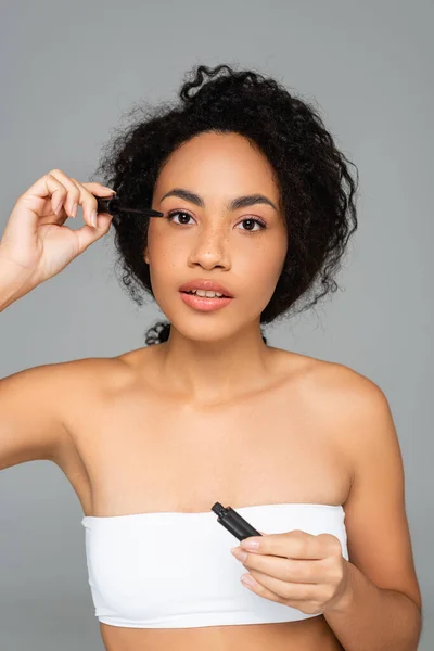 African American Woman Looking Camera While Applying Mascara Isolated Grey — Stock Photo, Image