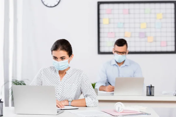 Donna Affari Maschera Medica Utilizzando Laptop Vicino Uomo Affari Sfondo — Foto Stock