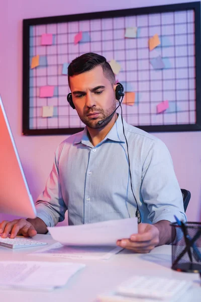 Operator Headset Zoek Naar Papier Buurt Van Computer Monitor — Stockfoto