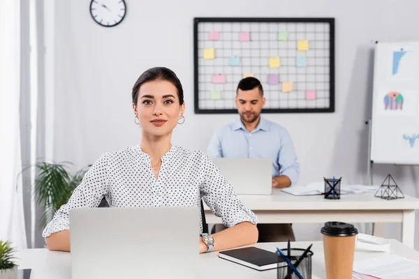 Mulher Negócios Alegre Sorrindo Perto Laptop Mesa Colega Trabalho Fundo — Fotografia de Stock