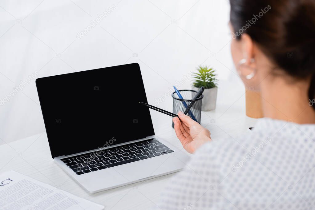 blurred businesswoman looking at laptop with blank screen