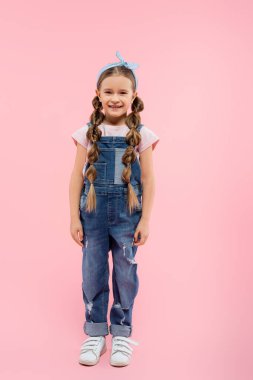 Gülümseyen ve pembe üzerinde duran mutlu bir çocuk.