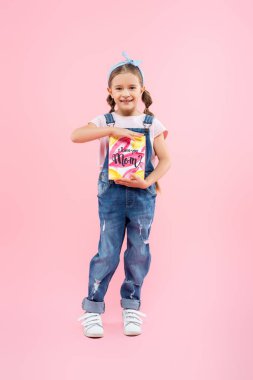 Elinde tebrik kartı olan mutlu bir çocuk. Seni seviyorum anne. Üzerinde pembe harfler var. 