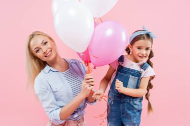 Mutlu anne ve kız pembe üzerinde izole edilmiş balonlar tutuyor.
