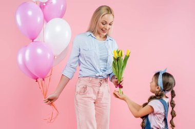 Çocuk mutlu anneye lale veriyor pembe balonlarla ayakta duruyor 