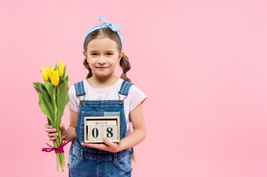 Mutlu çocuk elinde lale ve tahta küplerle 8 Mart 'ta pembe harflerle izole edilmiş. 
