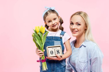 Mutlu çocuk elinde lale ve tahta küplerle 8 Mart 'ta annesinin yanına pembe harflerle izole edilmiş. 