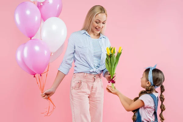 Criança Dando Tulipas Para Mãe Feliz Com Balões Isolados Rosa — Fotografia de Stock