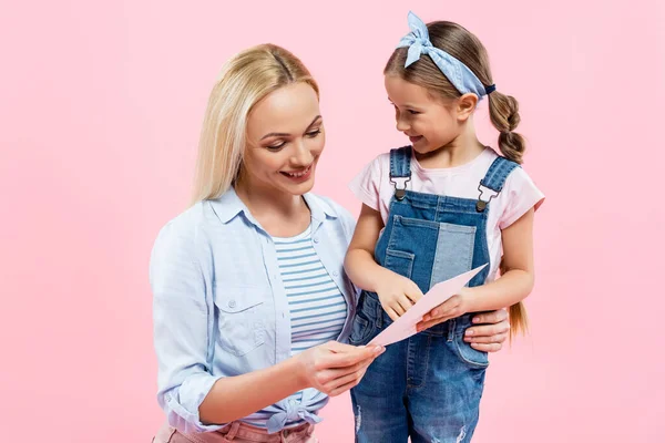 Niño Feliz Sosteniendo Tarjeta Felicitación Cerca Madre Aislada Rosa — Foto de Stock