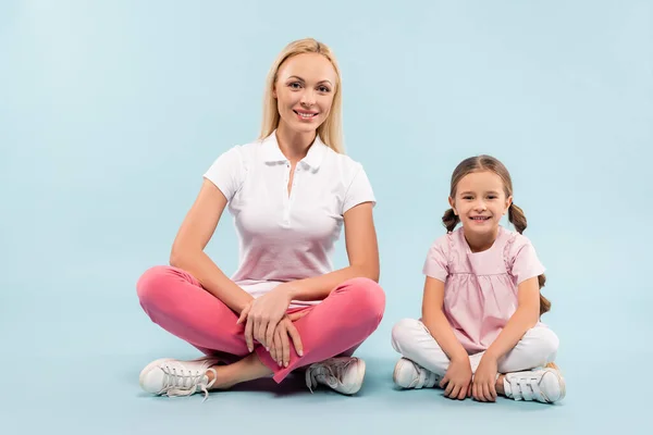 Glad Mor Och Barn Sitter Med Korsade Ben Blå Bakgrund — Stockfoto