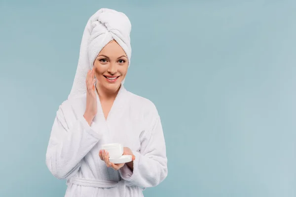 Mulher Feliz Roupão Segurando Recipiente Aplicando Creme Facial Isolado Azul — Fotografia de Stock