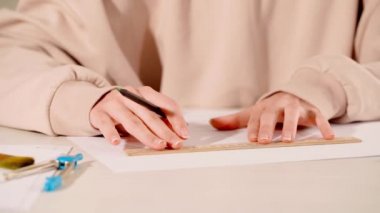 Cetvel kullanarak kağıda çizgiler çizen bir kadın görüntüsü