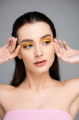 brunetka mladá žena se žlutými očními stíny odvracející izolované na šedé