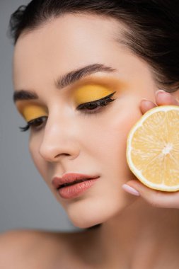 Gri renkte, olgun limonun yarısını tutan genç kadına yaklaş. 