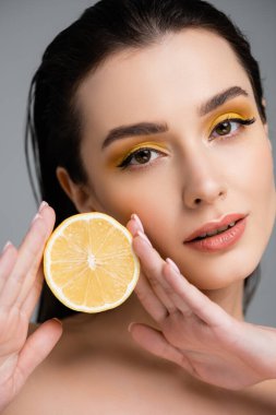 Gri renkte sulu limonun yarısını tutan esmer genç bir kadın. 