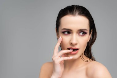 Pembe göz farları ve çıplak omuzları olan, tırnaklarını yiyen genç bir kadın. 