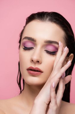 Makyajlı ve gözleri kapalı, pembe tenli genç bir kadın.