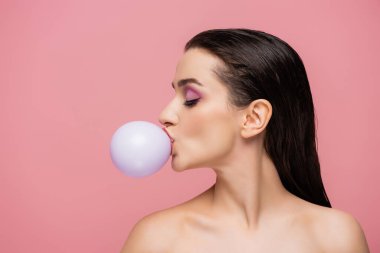 Çıplak omuzlu esmer bir kadının yan görünüşü. Pembe sakız üflüyor.