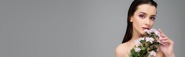 молодая женщина с розовыми тенями для глаз держа цветы изолированы на сером, баннер