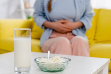 Cropped view of cottage cheese and glass of milk near woman with allergy on blurred background  clipart