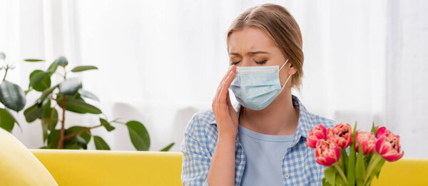 женщина в медицинской маске с аллергией рядом с тюльпанами на размытом переднем плане, баннер 