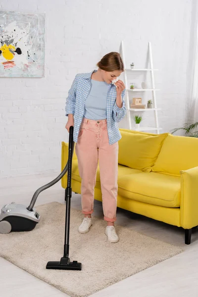 Woman with allergy on dust cleaning carpet with vacuum cleaner