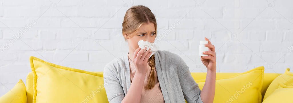 Woman with allergy holding napkin and pills at home, banner 