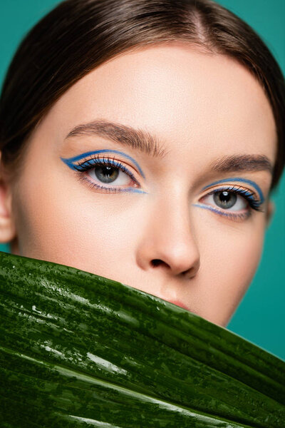 close up portrait of young woman with creative visage posing near shiny leaf isolated on green