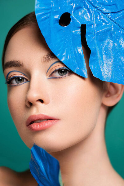 portrait of charming woman near blue glossy leaf isolated on green