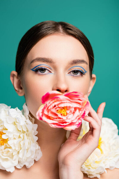 charming woman with fresh peonies looking at camera isolated on green