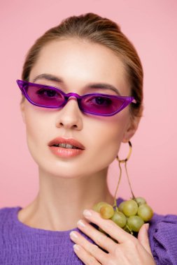 Pembe gözlüklü çekici bir kadın, pembe küpeli taze üzümlü.