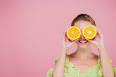 Gülümseyen kadın pembe üzerine ayrılmış olgun portakal parçalarıyla gözlerini kapatıyor.