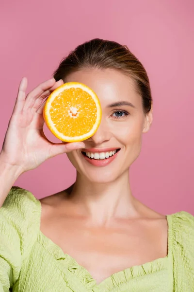 Усміхнена Жінка Прикриває Око Половиною Соковитого Апельсина Ізольовано Рожевому — стокове фото