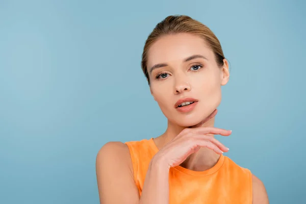 sensual woman with natural makeup looking at camera isolated on blue